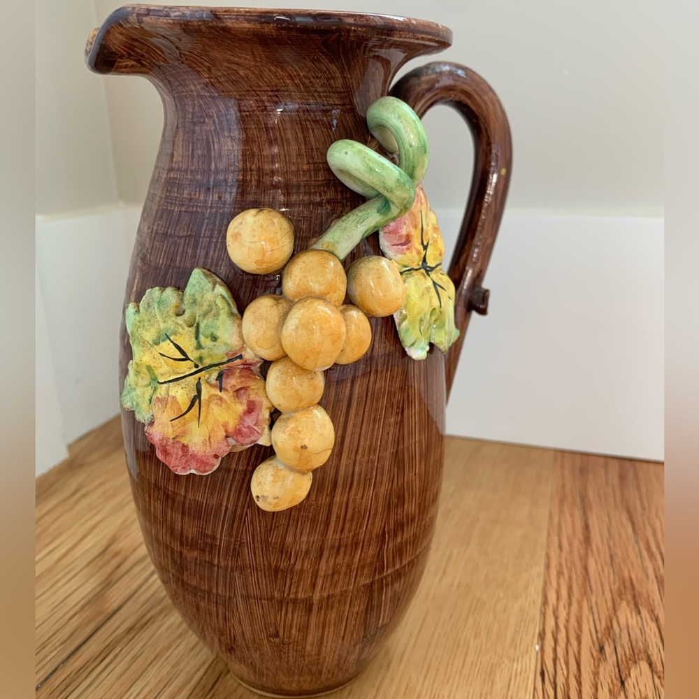 Vintage pottery pitcher or vase with embossed grapes and leaves.